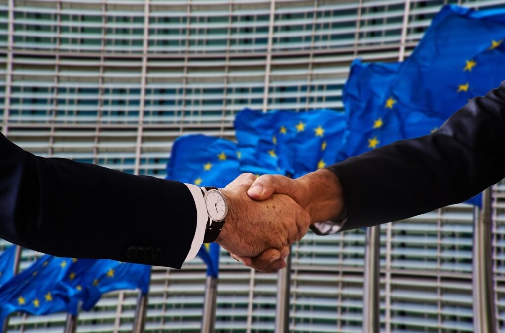 geralt via Pixabay, https://pixabay.com/photos/handshake-shaking-hands-europe-flag-4698429/